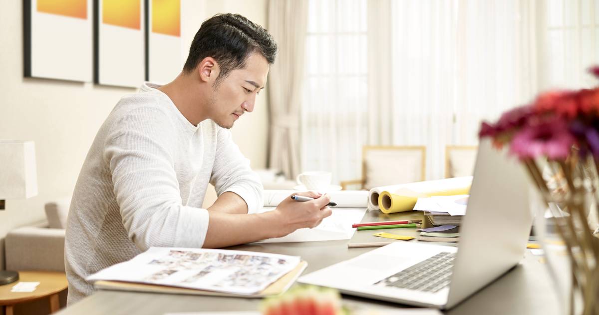 Aziatische man die thuis aan het werk is al designer